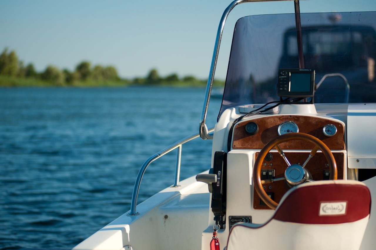 A yacht steering wheel with a serene water view during a bright summer day offering leisure and adventure.
